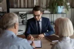 Attorney sits at desk with older couple and explains why excessive trading is illegal.