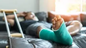 A man lies with a broken foot in a cast.