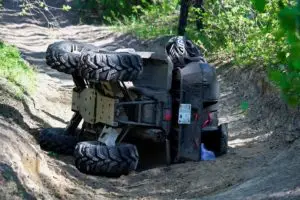 An ATV has flipped on its side on a dirt path.