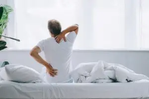 man in bed with neck and back pain