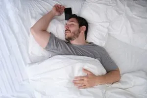 man sleeping in bed with his phone