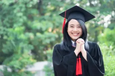 A smiling woman in her college cap and gown.