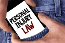 A hand removing a mobile phone from a pocket, with the phone displaying the text "Personal Injury Law"