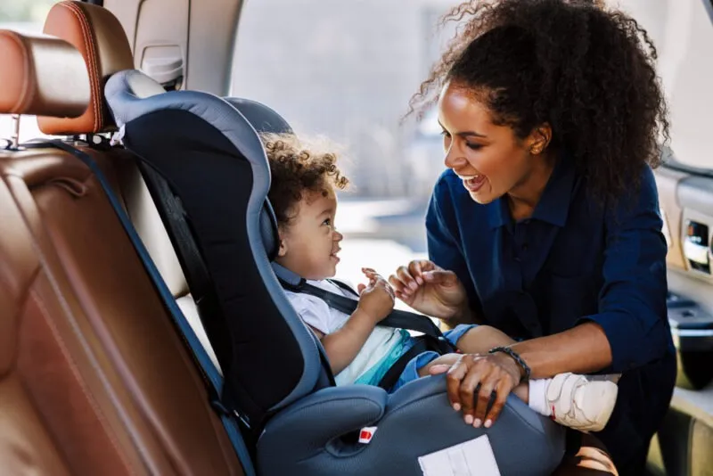 A mother buckling her baby into a car seat. You can ask a lawyer, “What are South Carolina’s car seat laws?”