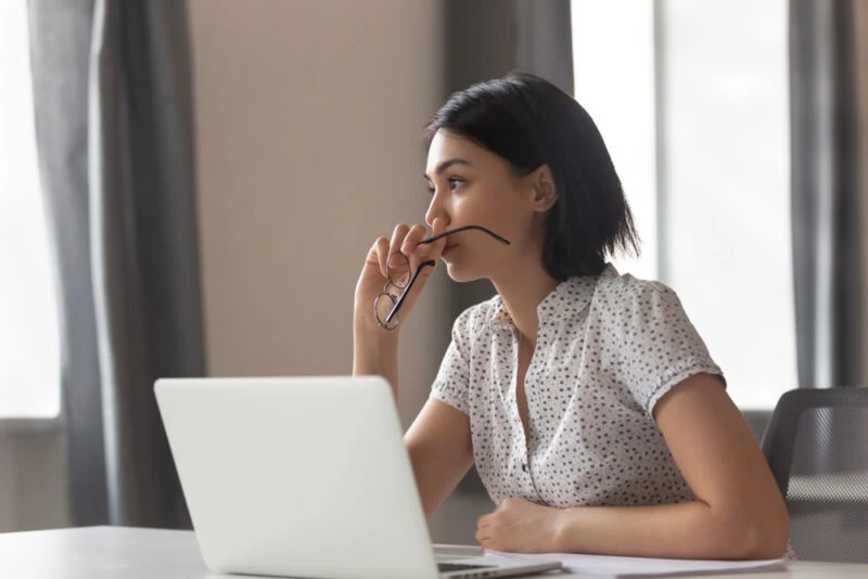 A thoughtful woman at her computer, wondering, “How much does it cost to sue someone?”