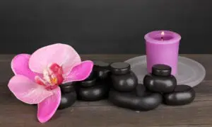spa-stones-with-orchid-flower-candle-wooden-table-grey-background