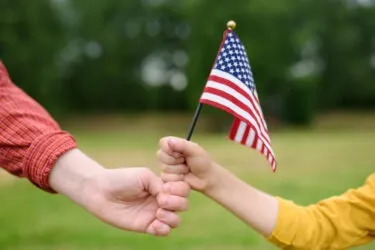 A woman and a little child hold an American flag. How long does it take to get a family-based green card?