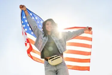 A woman celebrates while holding an American flag. Learn what happens after RFE approval.