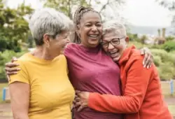 group of older women on Social Security Disability smiling and hugging in the park