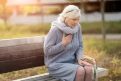 A woman sitting on a bench with chest pain could qualify for Social Security Disability for heart disease in Greenville, SC.