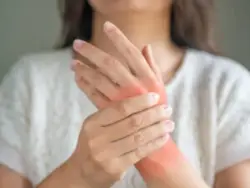 a young woman with rheumatoid arthritis is grasping one hand with the other