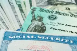 Several 100-dollar bills fanned out beneath a US Treasury check and a Social Security card to illustrate SSDI and SSI benefits increasing for millions of recipients in 2024