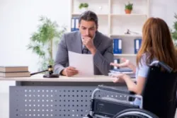 A disability lawyer reviews medical records for a client in a wheelchair and explains mobility and orthopedic conditions that qualify for disability benefits.