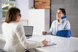 A woman in a neck brace and an arm sling consults a Social Security Disability lawyer about what to expect at her Social Security Disability interview.