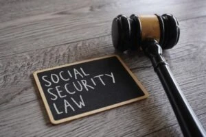 A gavel rests next to a chalkboard that says, “Social Security Law,” leading one to wonder how to choose a good Social Security Disability lawyer.