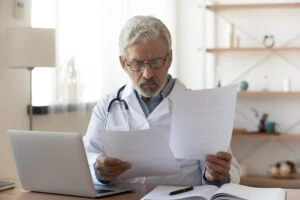 A doctor reviews his letter before delivering it. He knows this letter will influence his patient’s SSDI claim.