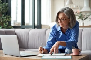 A woman applying writes notes on paper after learning she has received a fully favorable disability decision from the Social Security Administration (SSA). Such a decision means the SSA agrees you are disabled and approves your benefits claim. Learn more from a Social Security Disability benefits attorney.