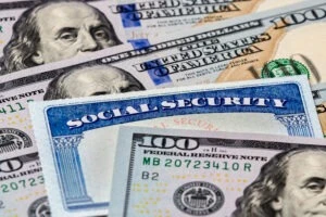 A social security card sits behind several bills of United States currency, leaving one to wonder: Why was my SSI payment reduced this month?