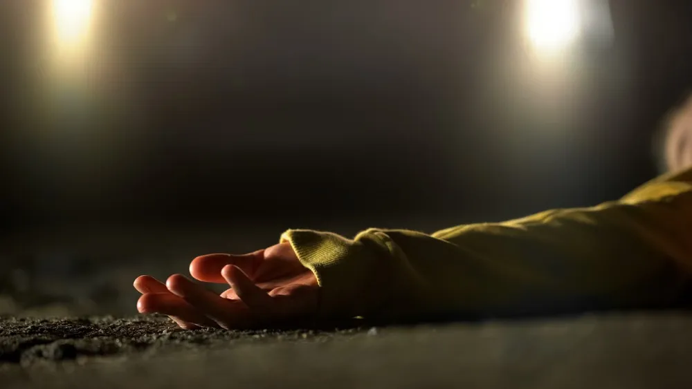 A person is lying in the road at night. Only their arm is visible with the palm up. There are headlights visible in the background of the image. Rockpoint Legal Funding provides cash advances for plaintiffs in wrongful death lawsuits.
