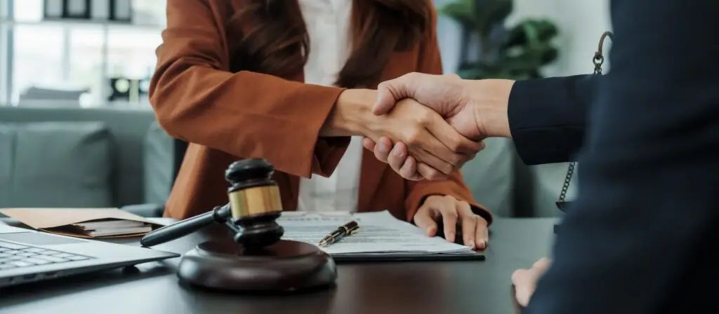 client and lawyer shaking hands near a gavel