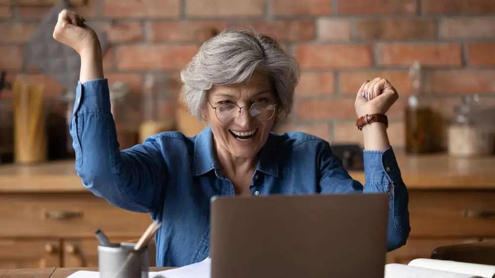 excited older woman happy to see loan went through on computer