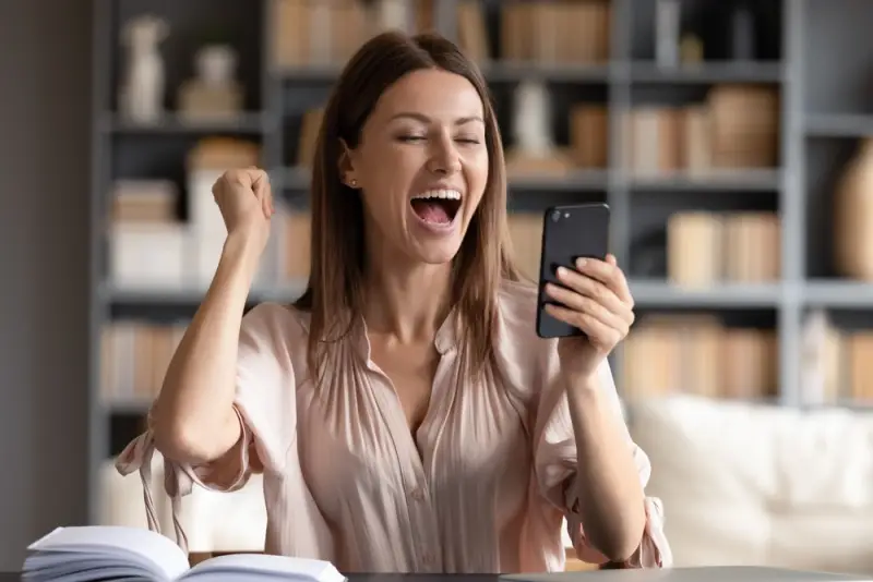 excited woman seeing loan went through on her phone