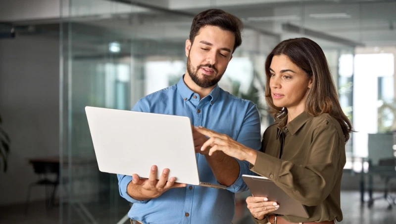 Man explaining pre-settlement funding details to woman by presenting information on laptop.