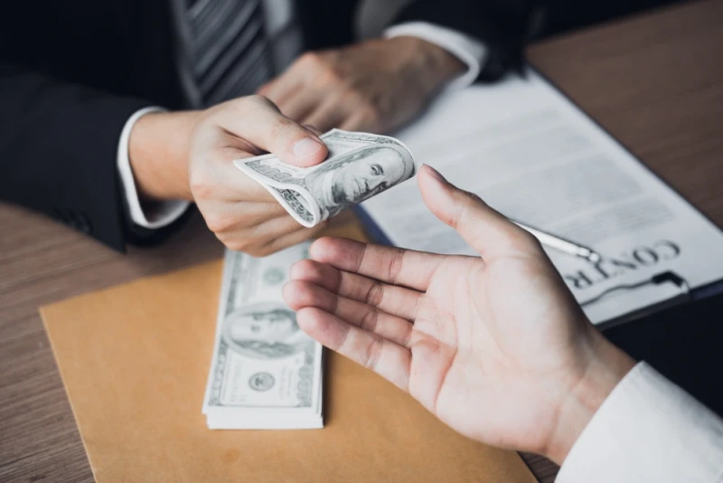 Man in suit handing over pre-settlement funding money to another person