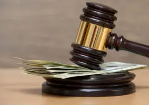 A gavel rests on a small stack of hundred dollar bills.
