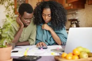 A stressed couple sits at the table calculating their bills