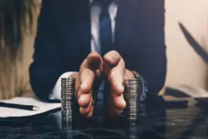 An insurance adjuster with hands between coins.