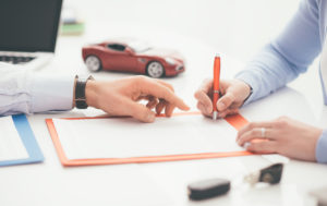 man-signing-loan-paperwork-near-toy-car