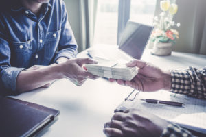 person-being-handed-a-bundle-of-cash