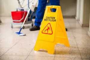 worker mopping next to a wet floor sign