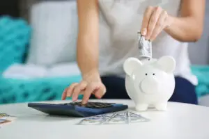 female hand putting money into piggy bank