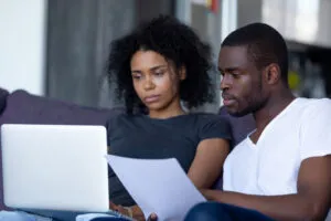 black couple struggling while reviewing their budget on a laptop