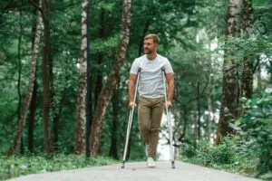 man on crutches walking in woods