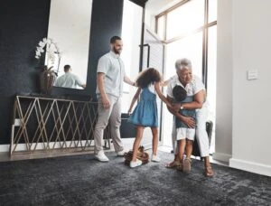 A woman hugs her grandchildren upon entering a home while another family member looks on in Georgia. You can consult a family lawyer on when a parent can deny a grandparent visitation and pursue your legal options.