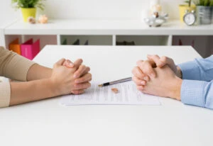 A couple sits at a table with their divorce papers and wedding rings. To file for divorce in Georgia, you must file a divorce petition with the Superior Court in the county where you or your spouse resides. A family lawyer who can represent you in divorce proceedings.