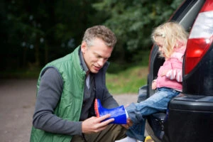 A man co-parenting his daughter puts a boot on her foot before a walk. A family lawyer can advise you of the rights custodial parents have vs. those of non-custodial parents and how you can take legal action to protect them.