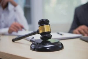 A gavel, with a lawyer explaining to his client if they have to go to court for a car accident in the background.