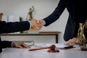 A lawyer shaking hands with a client who is wondering if they should get a lawyer for a minor car accident.