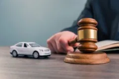 judge-holding-a-gavel-by-a-small-car