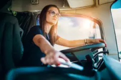 Female truck driver reaching for cell phone. Distracted driving can cause accidents; when it does, reach out to a Brownsburg truck accident lawyer.