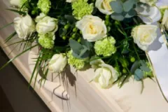 A coffin with a funeral flower arrangement on top of its lid.