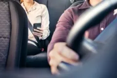 A rideshare passenger uses her phone. Contact an Indianapolis rideshare accident lawyer now.