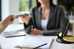A lawyer handing a client money. Contact us to learn how much compensation you can expect from a personal injury case.
