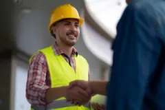 A construction worker shaking hands with a lawyer. Find out what qualifications your construction accident lawyer should have.