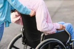 A medical professional wheels a spinal cord injury survivor out of a hospital in a wheelchair.