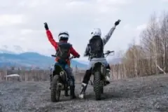 Two motorcyclists celebrating riding safely across difficult terrain.